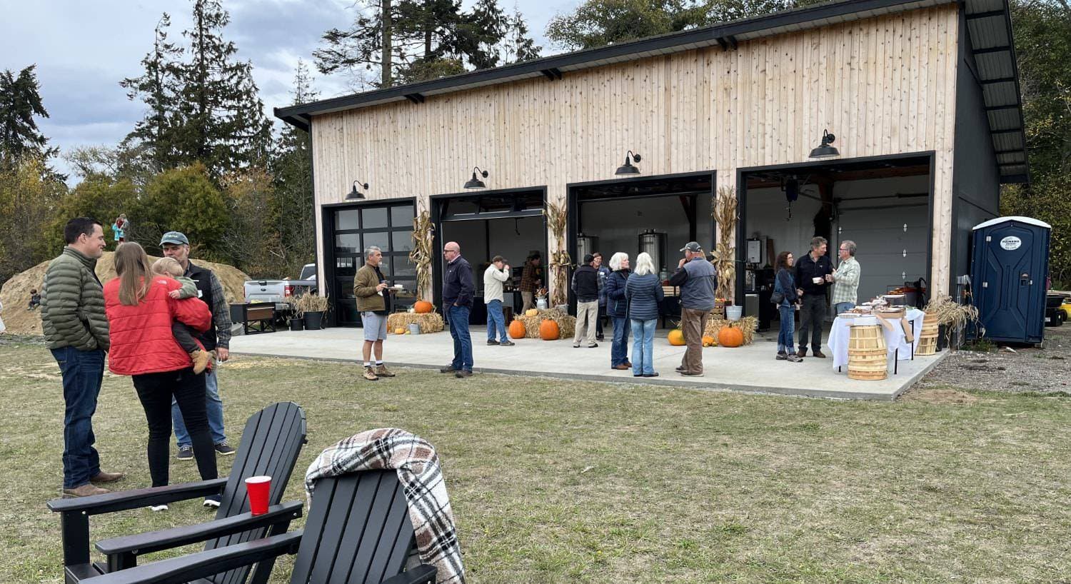 Cidery building with open garage doors set up for a fall inspired event with people visiting together