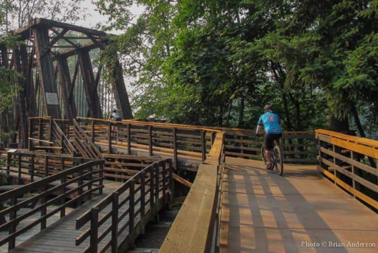 Person on bike riding on wooden trail with a large bridge