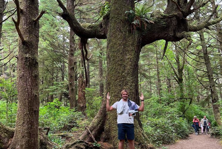 Man standing in front of large tree with his arms up in same shape as tree