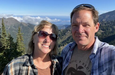 Man and woman smiling with mountain side in the background