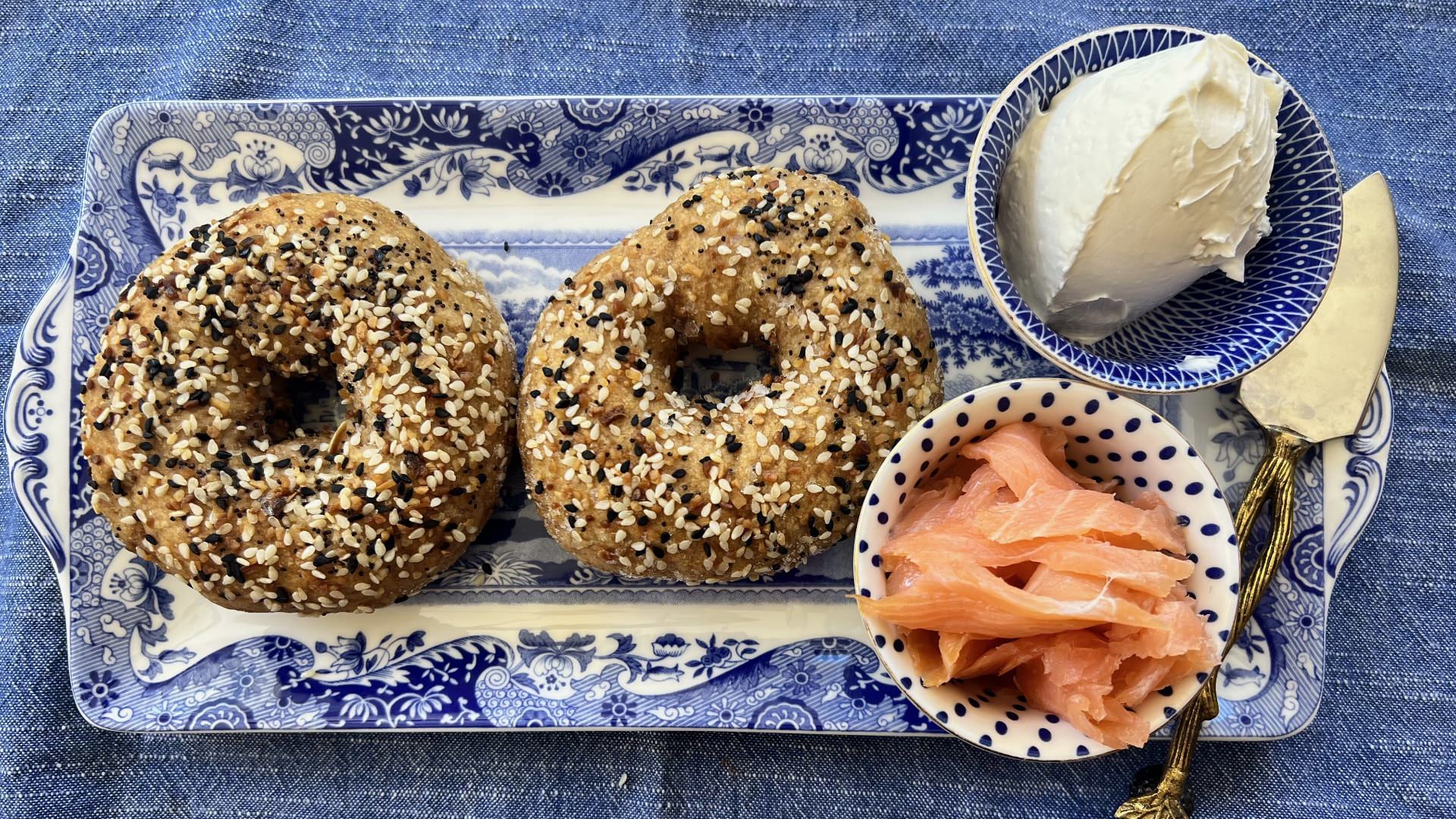 Close up view of bagels, salmon, and cream cheese on a blue serving platter