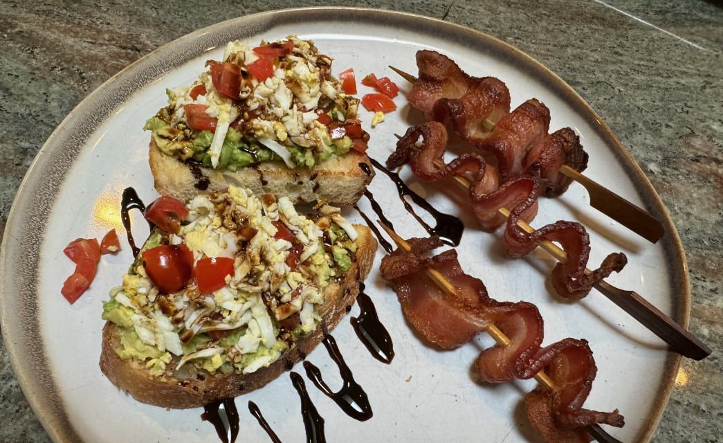 Close up view of avocado toast with skewered bacon