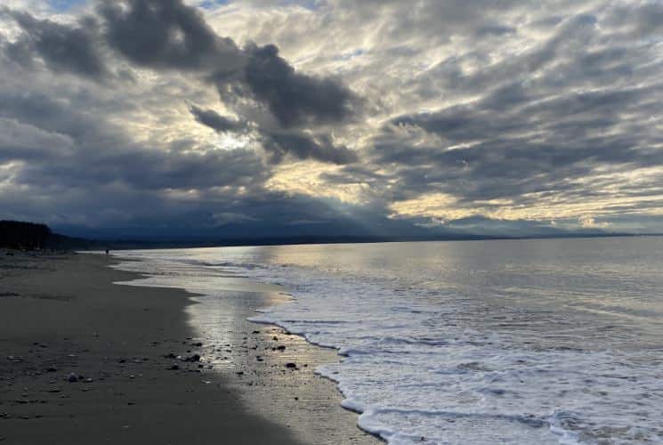 Light waves rolling on a sandy beach with cloudy skies